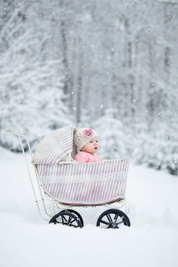 Baby girl in white wicker stroller winter scene